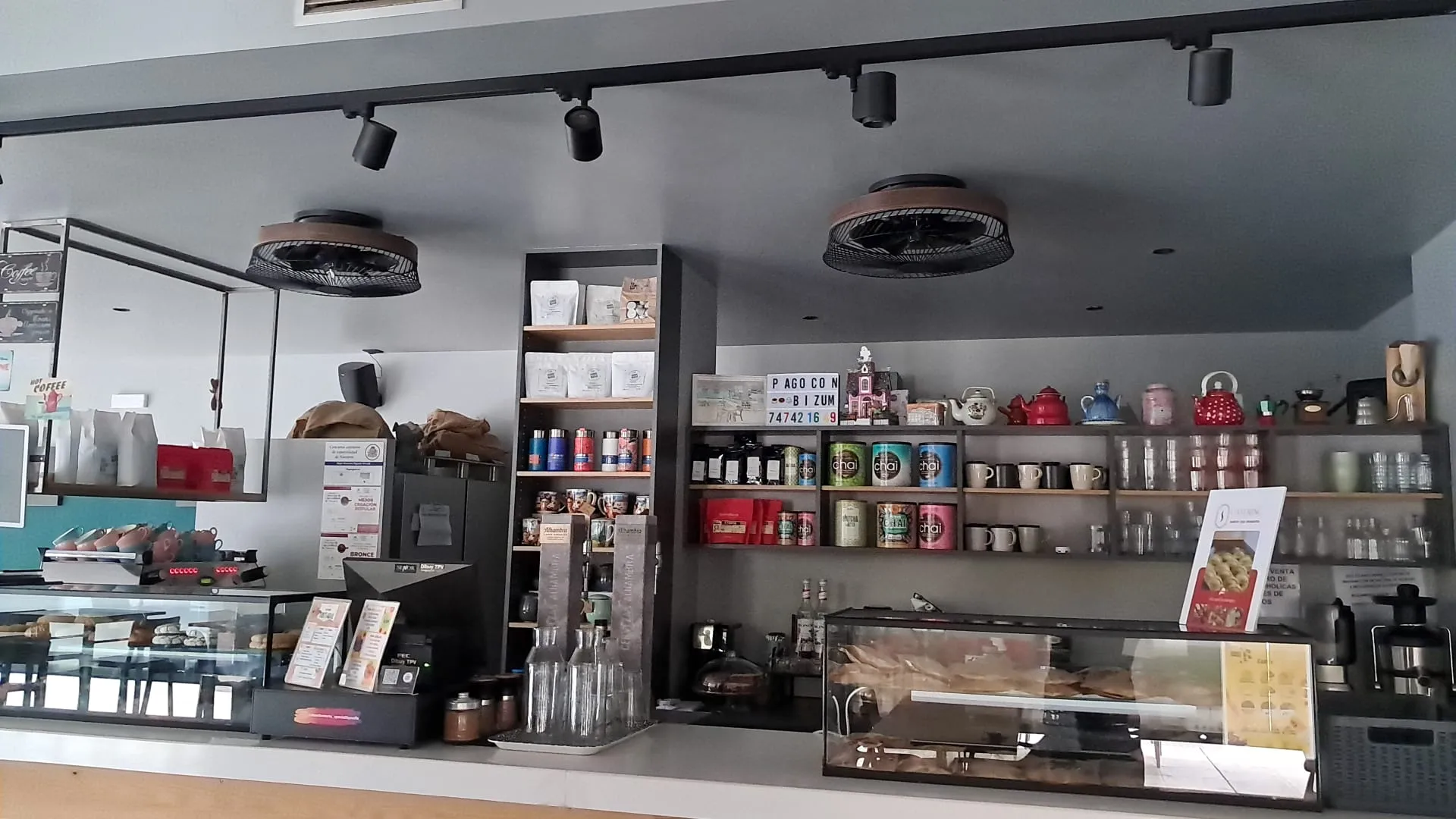 Estantería con cafés de especialidad y teteras tras la barra